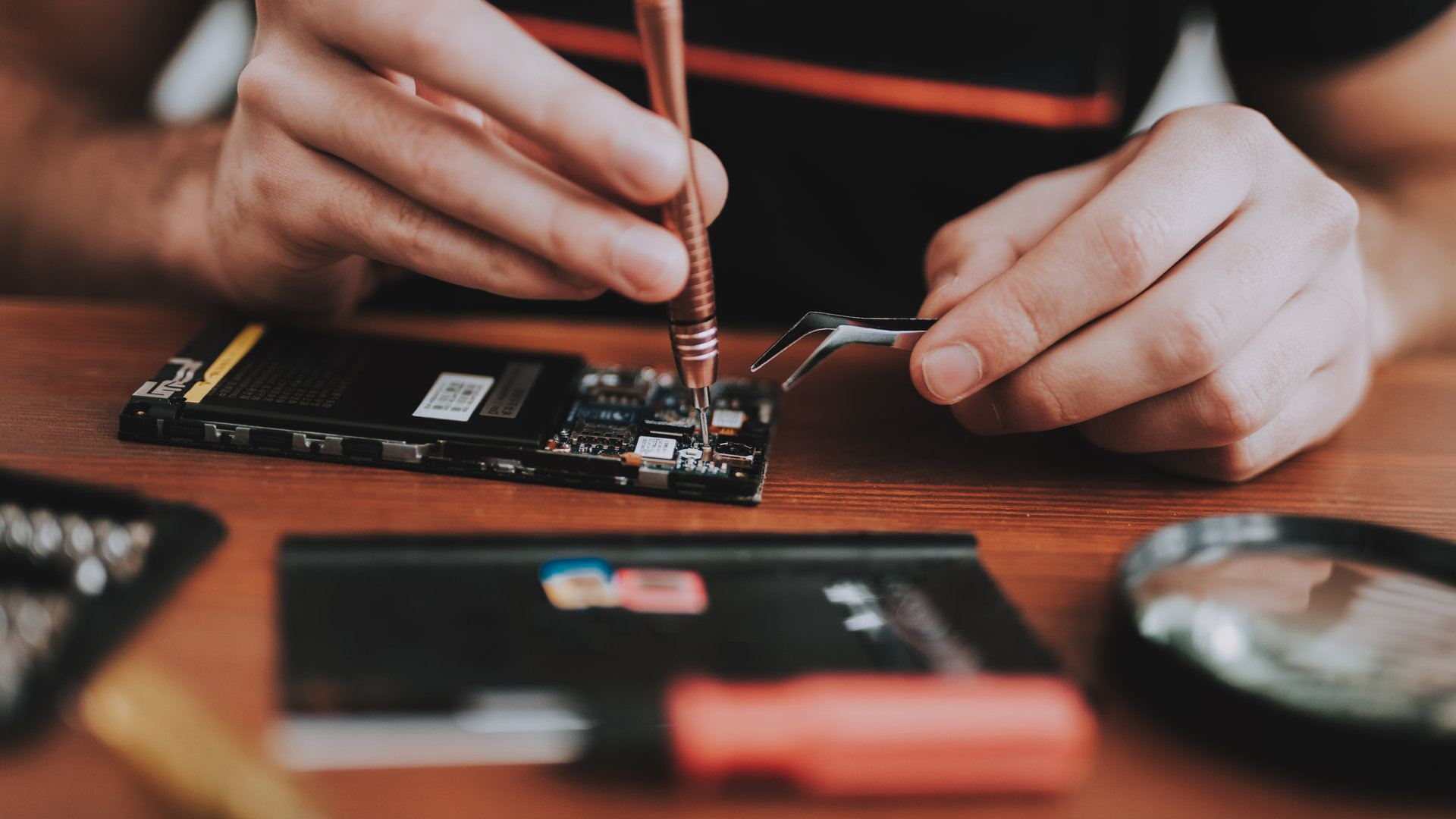 Close up. Young Man Repairing Mobile Phone. Repair Shop. Worker with Tools. Magnifying Glass. Digital Device. Tools on Desk. Electronic Devices Concept. Mobile Device. Smartphone Repair.